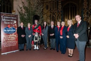 Tamworth Co-op funeral staff and Scottish piper standing next to Christmas tree