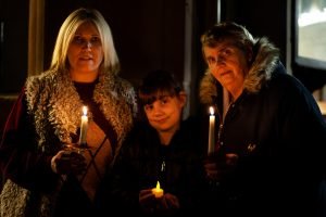 Mother, daughter and granddaughter hold lit candles at Tamworth Co-op Christmas Memorial Service